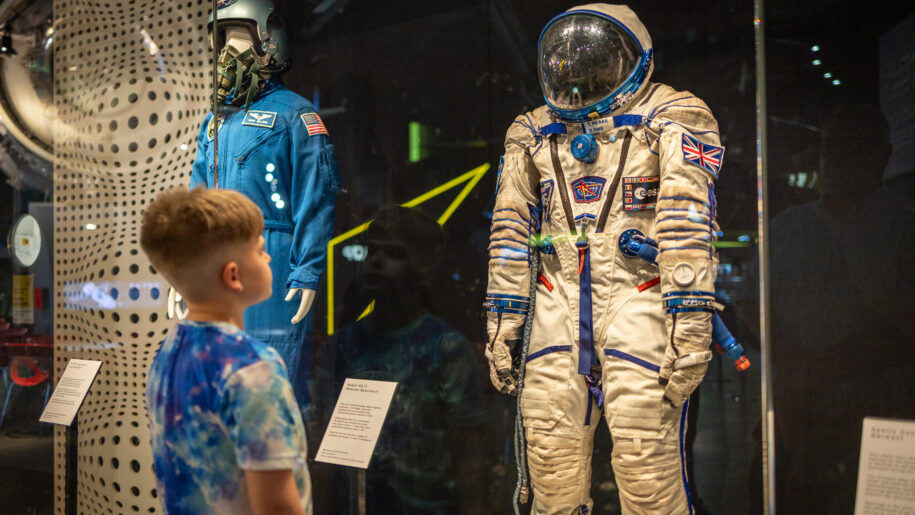 boy looking at astronaut suit