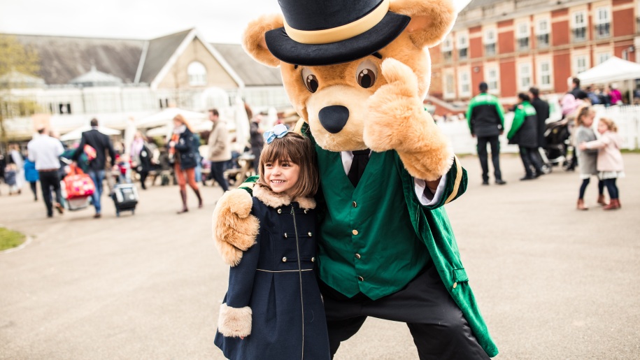 Girl with life-size Greencoat Bear mascot at Ascot