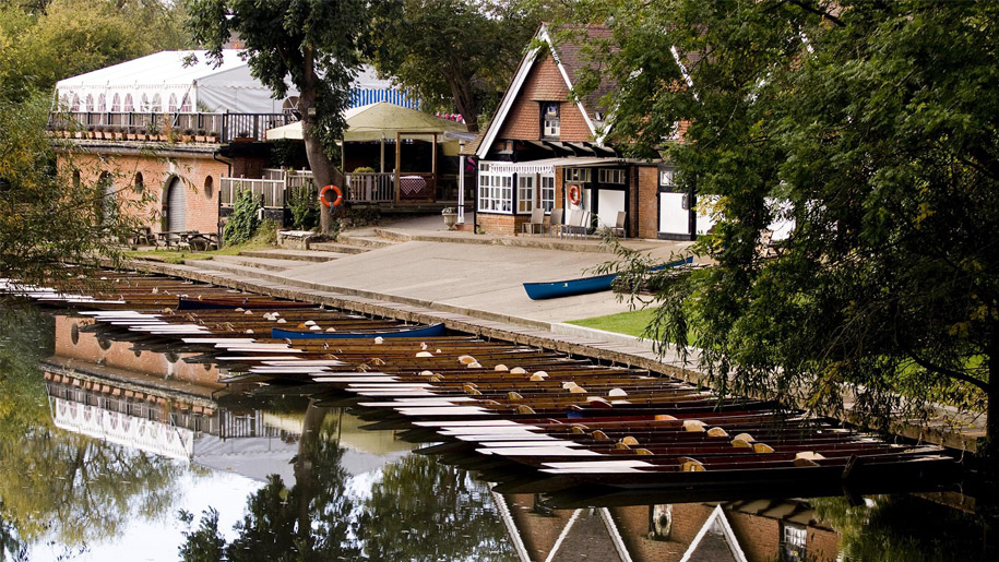 rowing boats on river outside boathouse