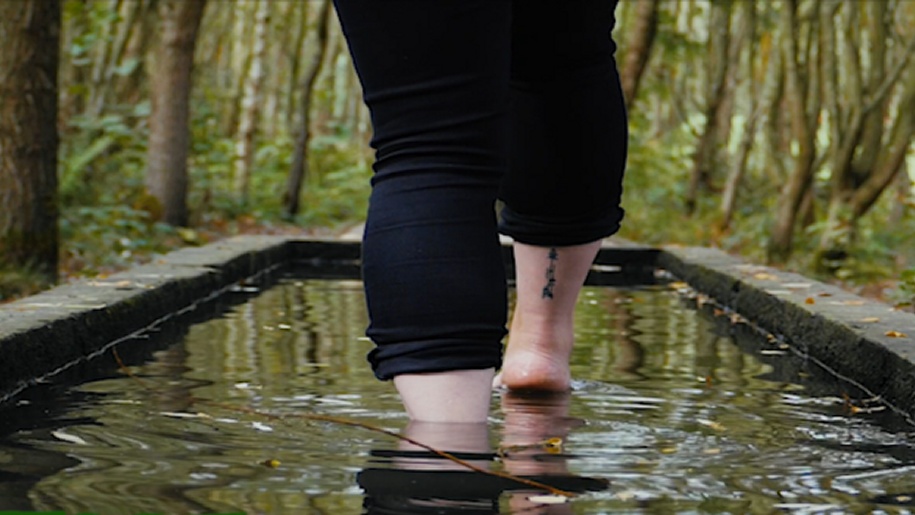 Two feet stepping through water on the Barefoot Walk at Conkers.