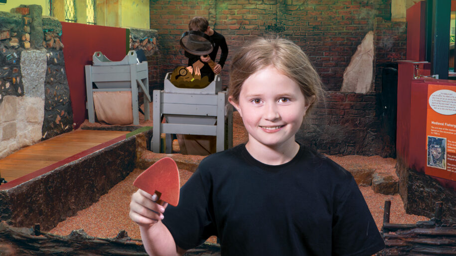 a young girl stands with a spade in front of the DIG exhibit at Jorvik