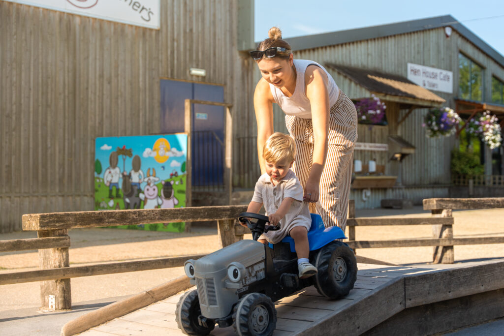 mother pushing young boy on tractor