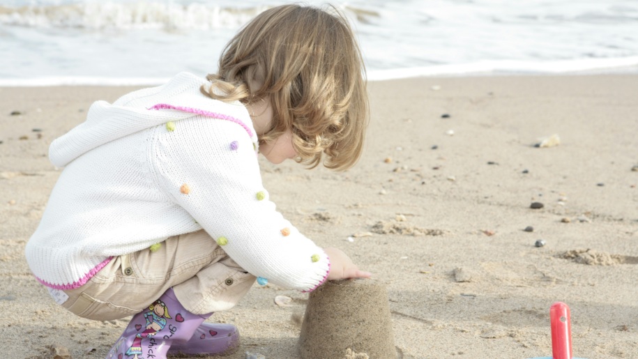 Young child building sandcastles on a beach.
