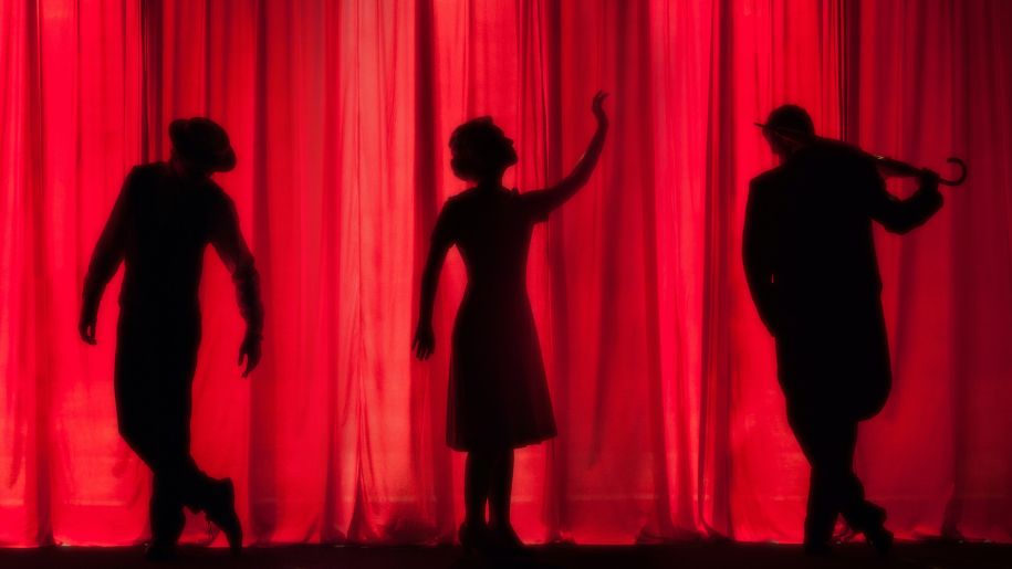 3 character silhouettes on a red theatre curtain