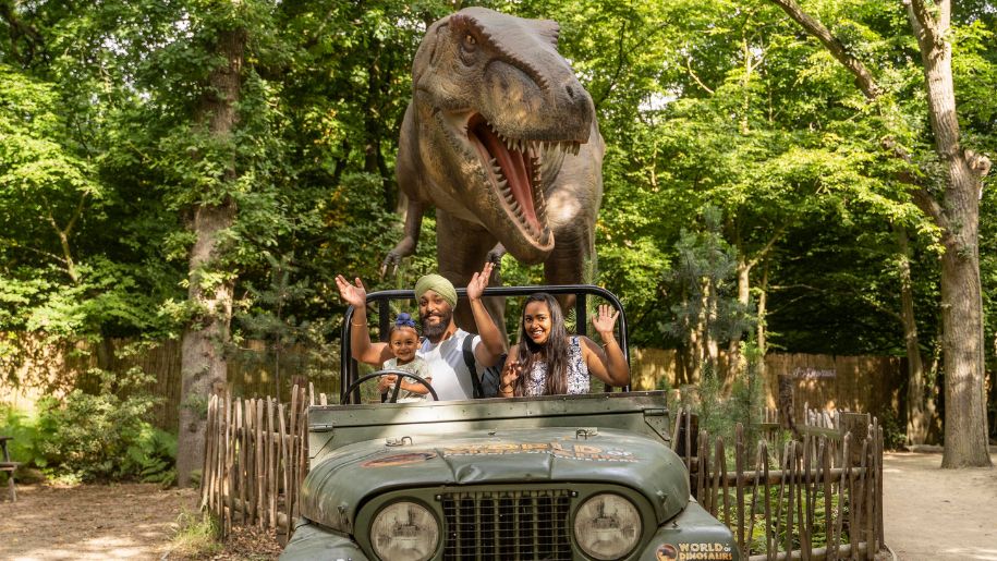 Family posing in a Jeep infront of a dinosaur
