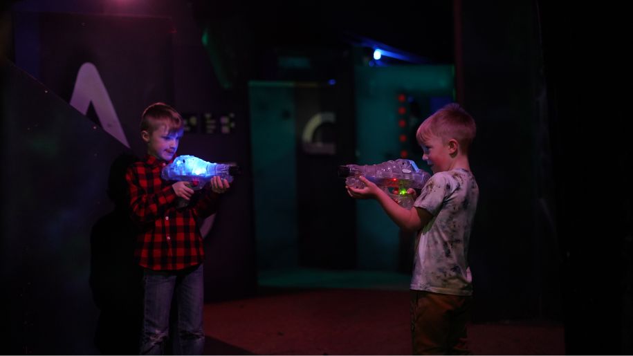 two children playing laser tag in a dark room
