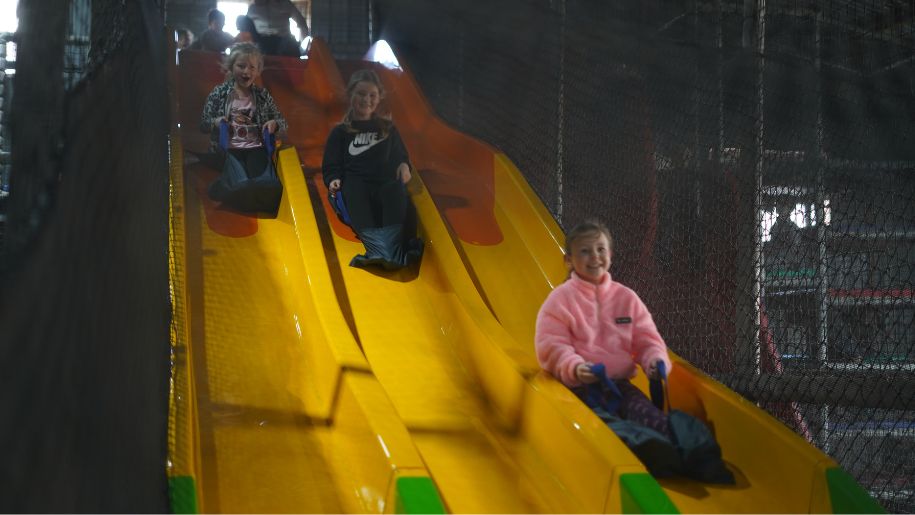 three children going down soft play slide