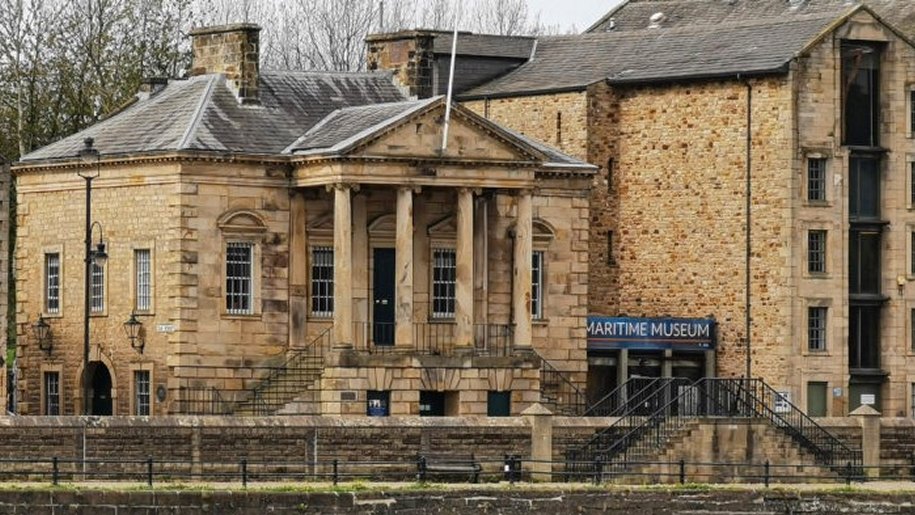 Large stone building and blue sign marking entrance to Maritime Museum.