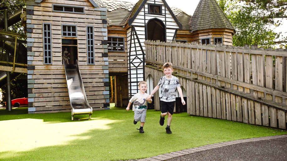 two kids run in a wooden playground