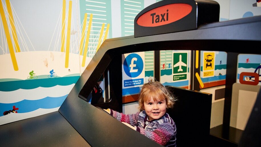 Young child in driving seat of a taxi at London Transport Museum