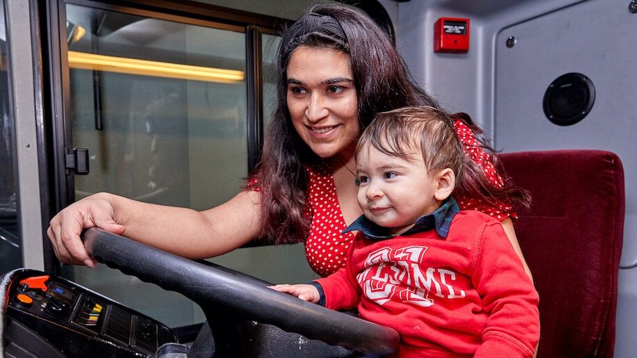 Mother and young child holding a steering wheel at London Transport Museum
