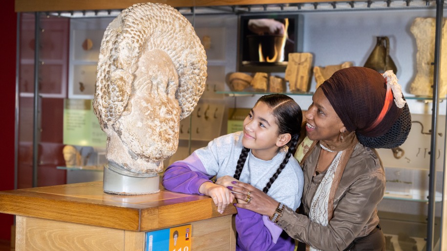 Child and adult looking at a stone Roman artefact.