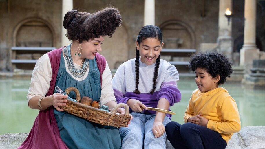 A costumed re-enactor and young visitors at the Roman Baths.