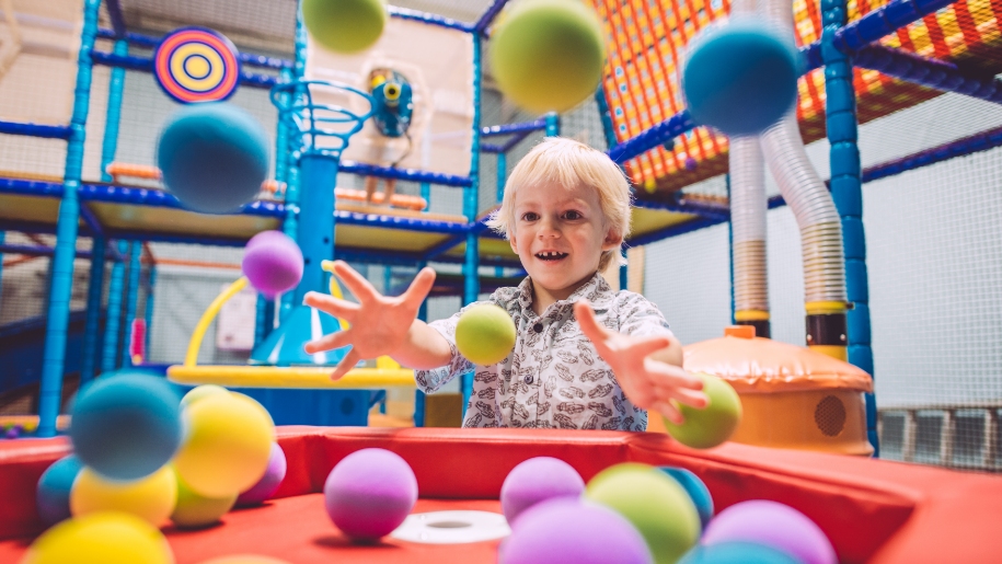 child playing with balls in soft play area