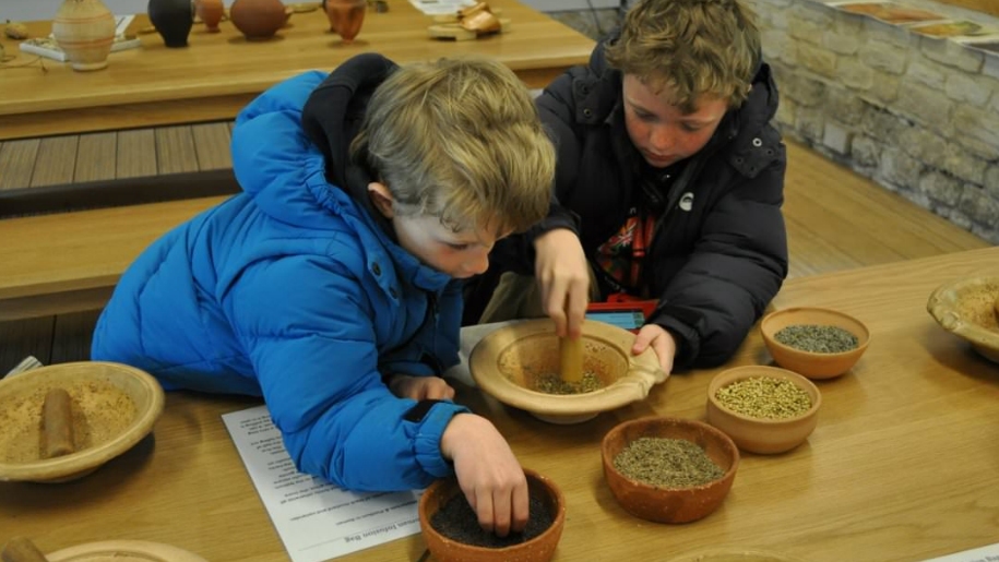 Children grinding grain at Chedworth Roman Villa in Gloucestershire.