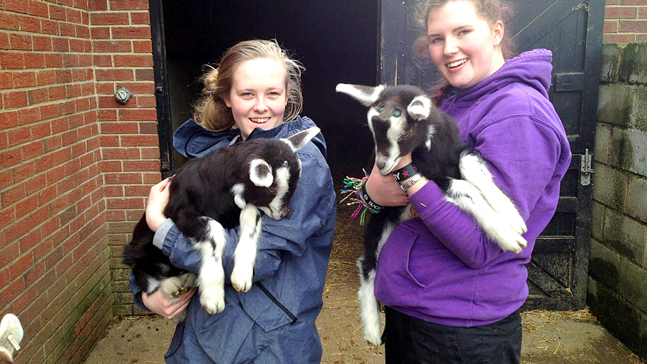 two girls holding goats