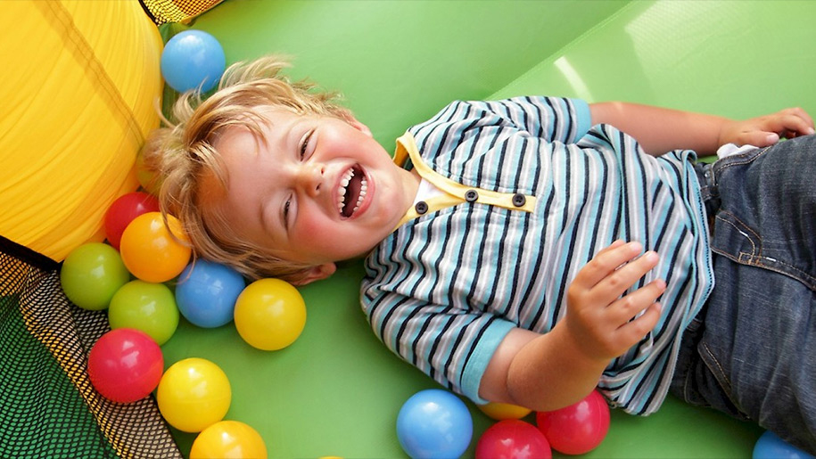 boy in soft play centre lying down laughing