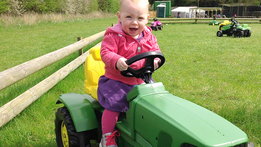 little girl on toy tractor