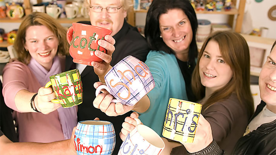 family holding mugs that they have painted