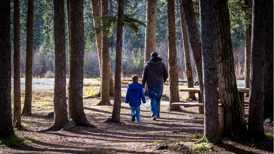 father and child walking in woods