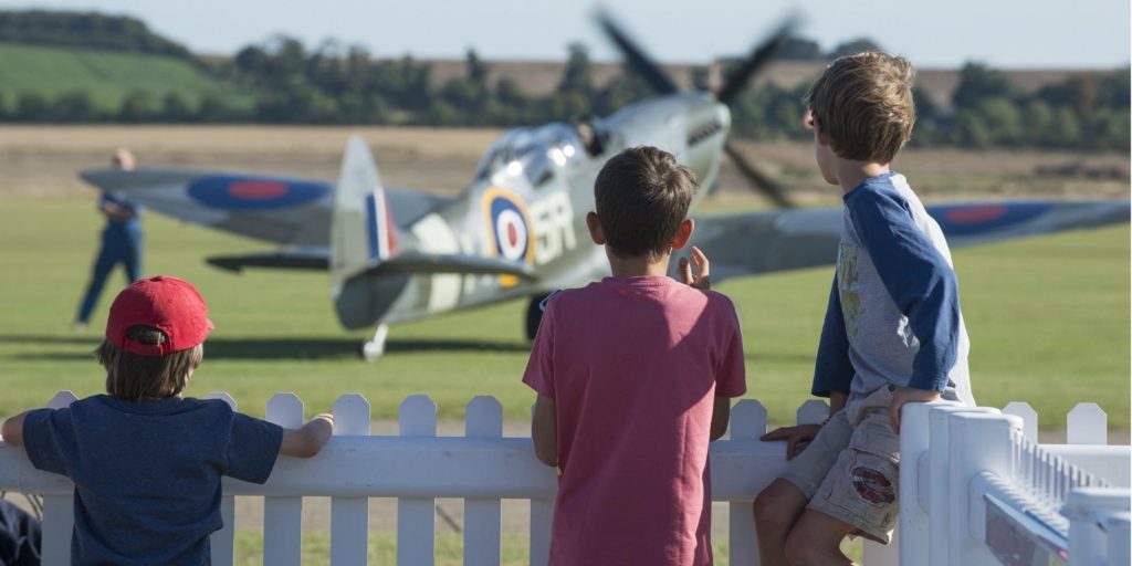 three boys looking at fighter plane