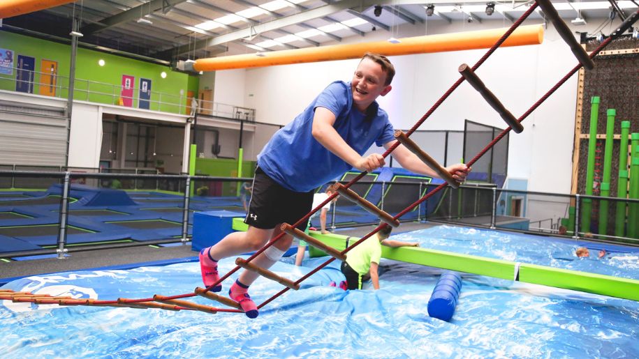 Boy on tightrope ladder on inflatable course at Jump In Abderdeen