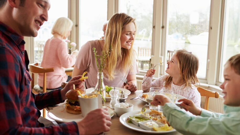 family happily enjoying a meal round a table in a busy restaurant
