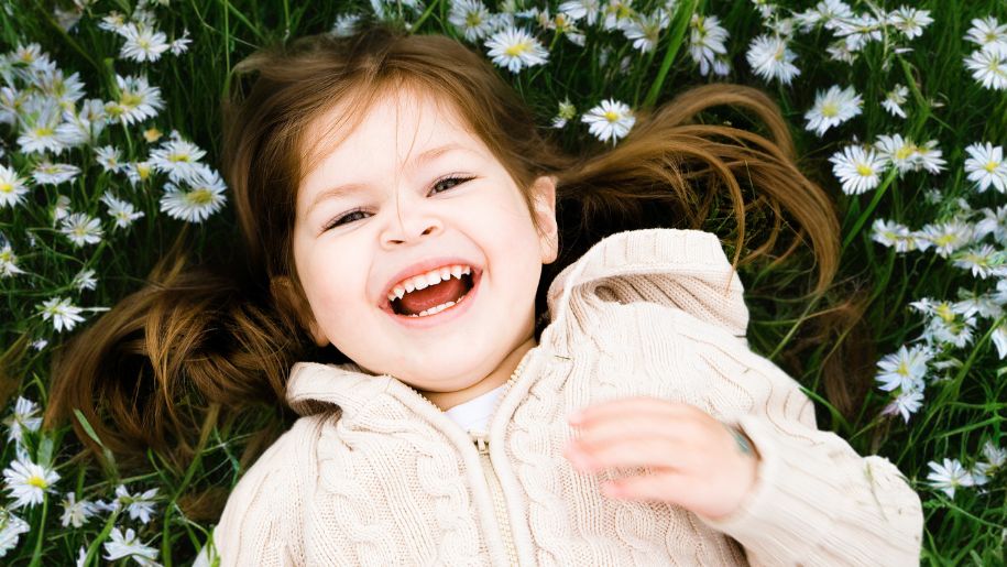 Young girl laughing whilst laying in daises