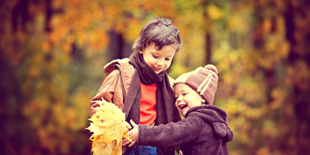toddler playing in autumn leaves