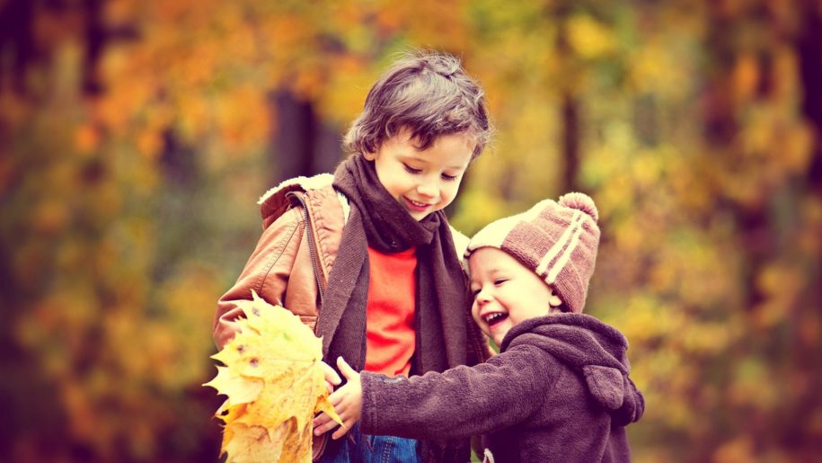 toddler playing in autumn leaves