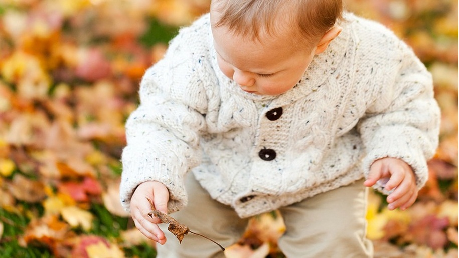 baby picking leaves off the floor