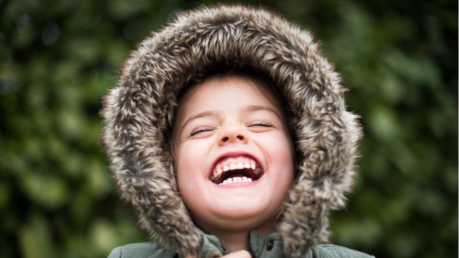 Child laughing wearing winter fur hooded coat