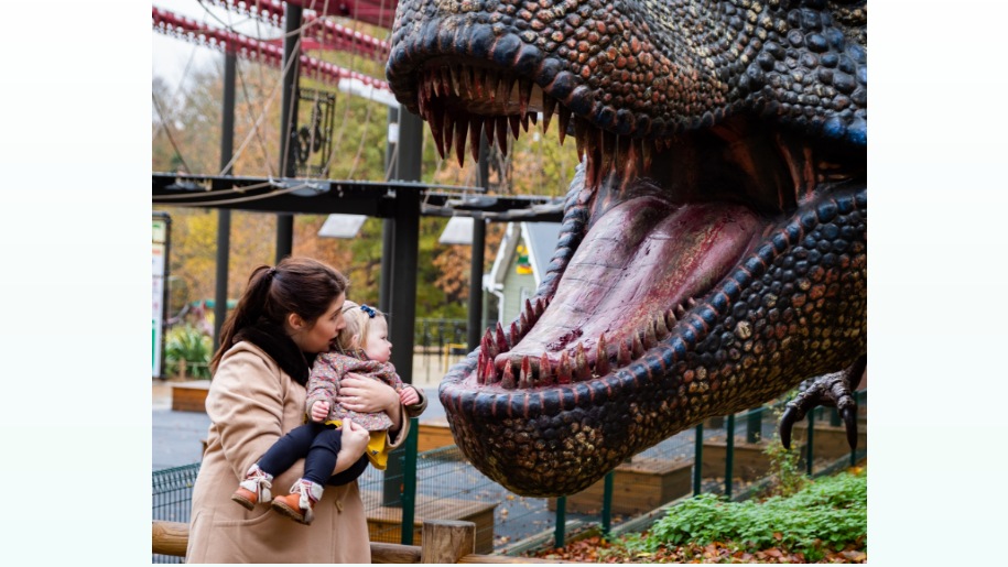 mother & baby standing in front of large dinosaur head