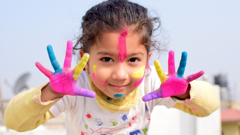 Young child with paint on their hands and face.