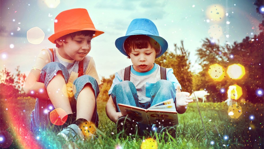 Two boys reading a book on the grass