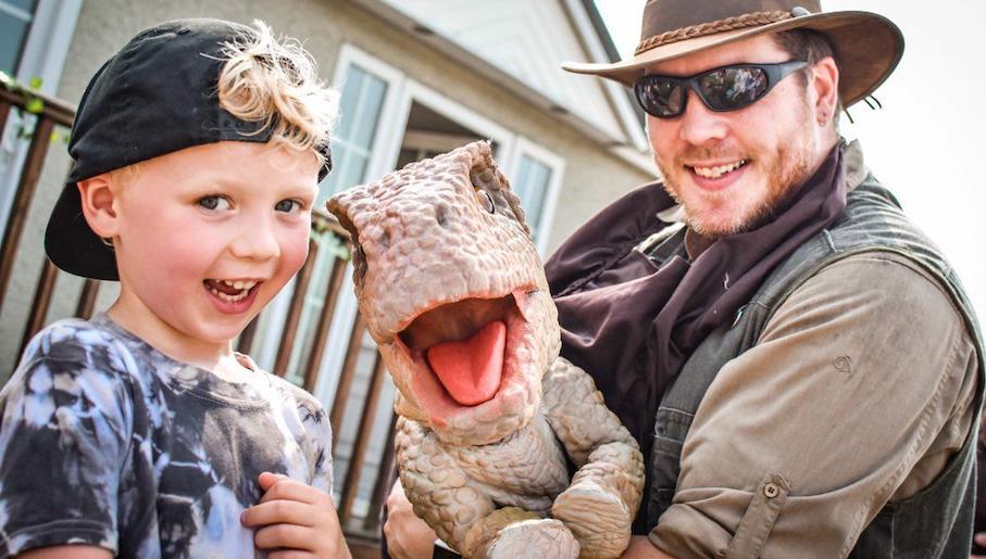 Boy and ranger wearing sunglasses with dinosaur at Whistlestop Valley