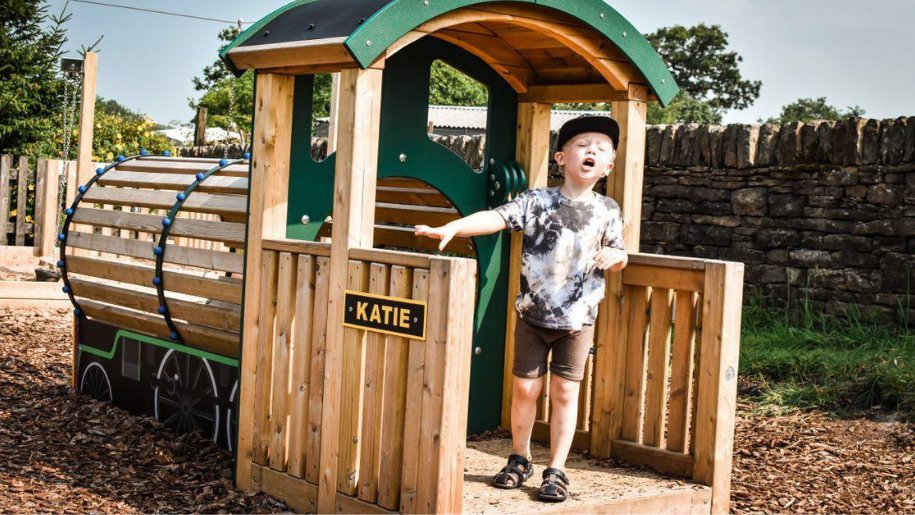 small boy playing on wooden train at Whistlestop Valley