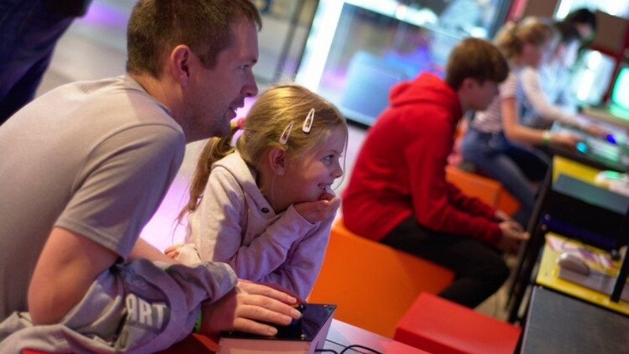 father and girl playing video game National Videogame Museum