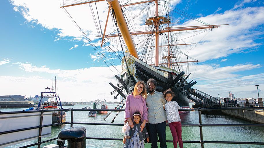 A family of 4 posing outside a grand ship in Portsmouth Historic Dockyard