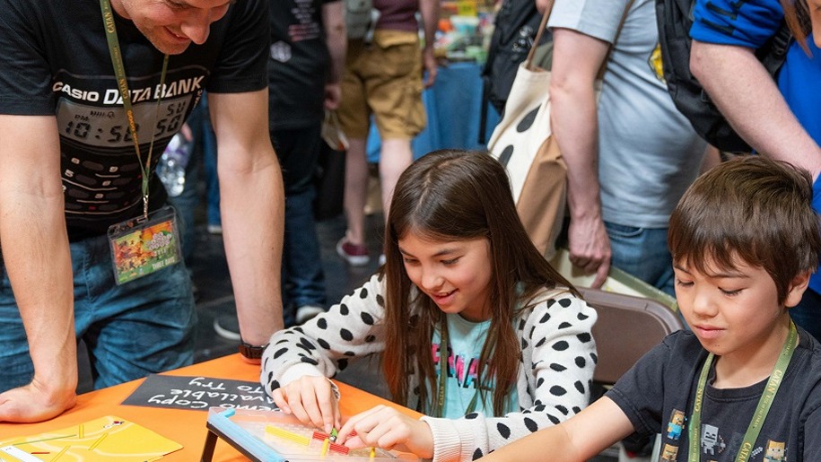 boy and girl playing gmae watched by day UK Games Expo