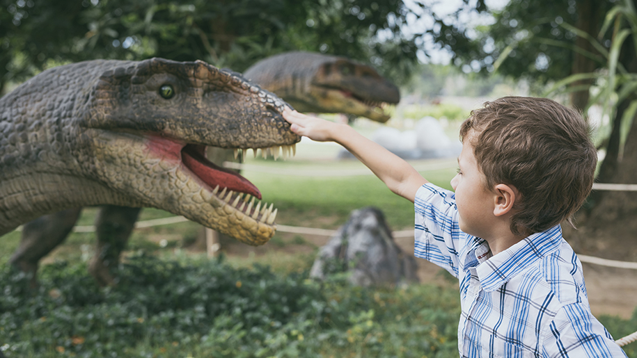 boy touching nose of dinosaur