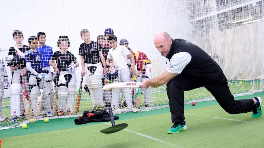 Cricket trainer with bat boys watching