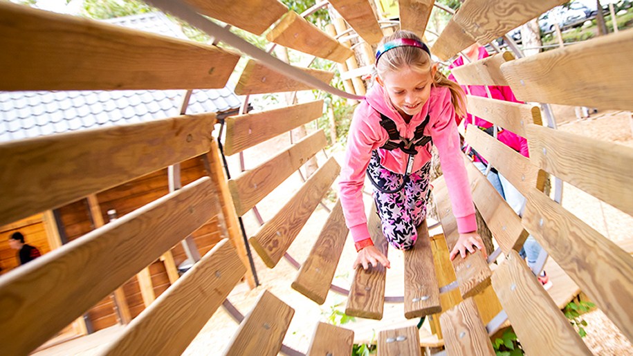 Child crawling through wooden tunnel at Go Ape