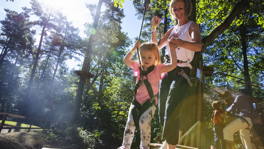 Parent helping young child to negotiate zip wire at Go Ape