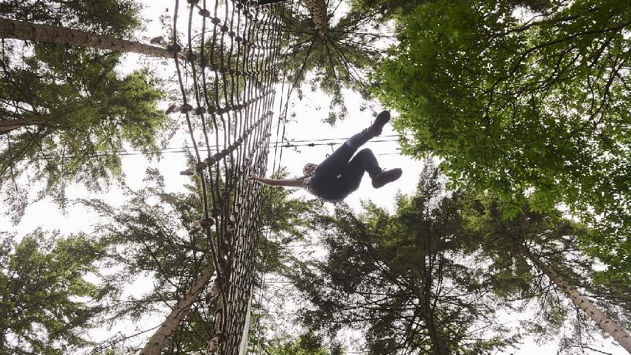Go Ape Cockfosters (Trent park London) girl swinging in treetops holding onto a rope wall
