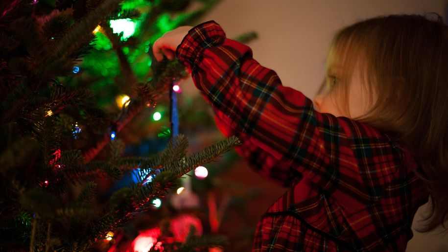 girl hanging christmas tree decorations