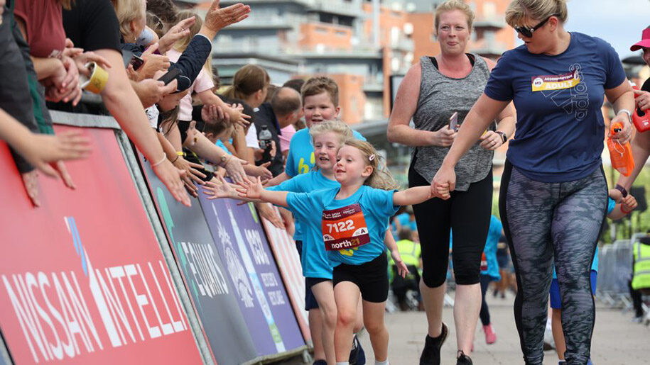 Great North Run children doing high five with crowd with two ladies