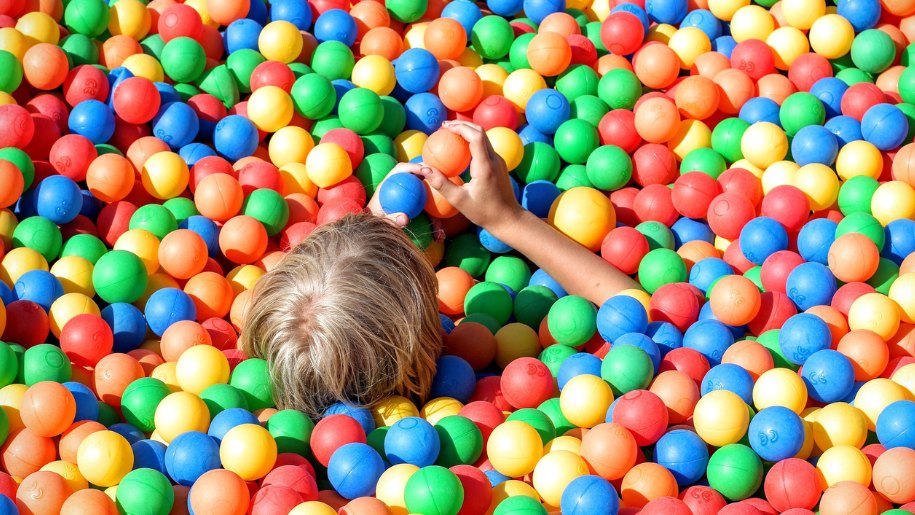 head of small child submerged in soft play ball pit