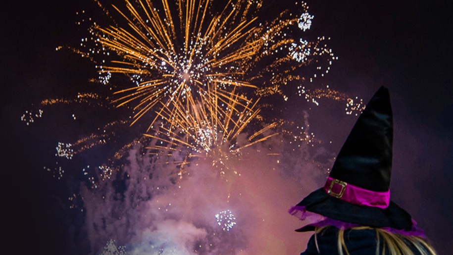 fireworks in night sky watched by spectator in a witch's hat