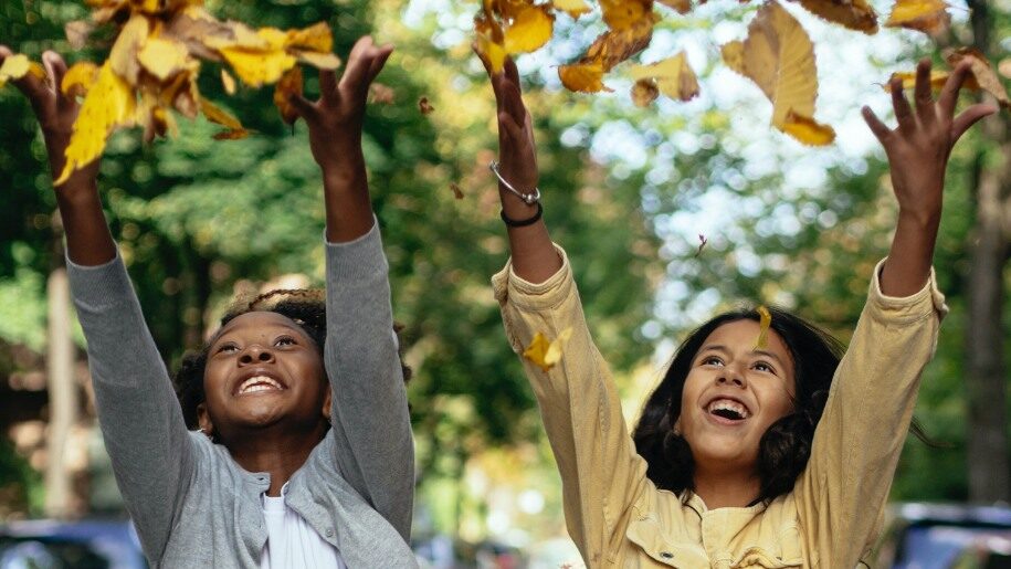 Children throwing autumn leaves up in the air.